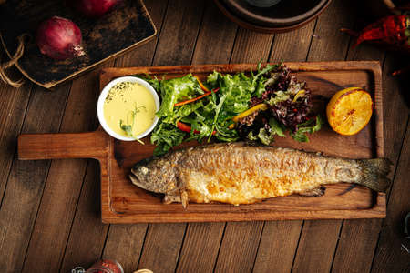 Homemade fried trout fish with sauce and salad