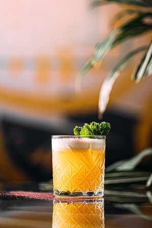 Yellow whisky sour cocktail garnished with mint