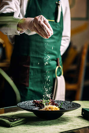 Chef making salad with parmesan in gourmet bowl