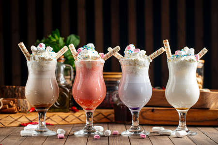 Four glasses of sweet milkshakes with biscuits