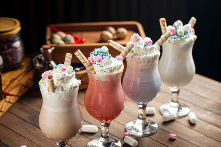 Four glasses of sweet milkshakes with biscuits