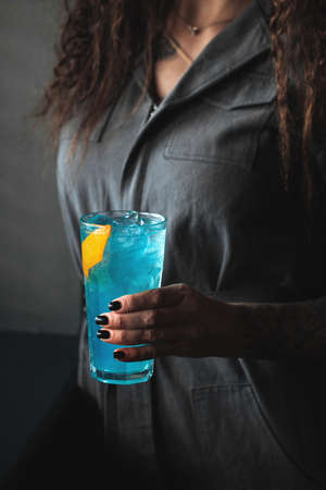 Woman holding blue cocktail in a highball with iceの写真素材
