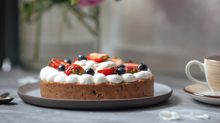 Side view on sweet creamy cake with berries and tea