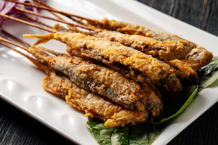 Portion of asian fried capelin skewers with onionの写真素材