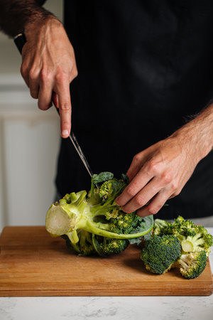 Chef cutting broccoli preparing mealの写真素材