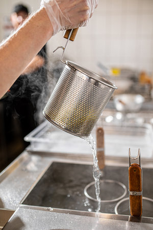 Chef drains the boiled noodles for ramen