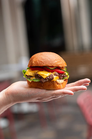 Cheeseburger on hand with cafe backgroundの写真素材