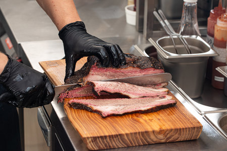 Cutting smoked brisket into slices in the kitchenの写真素材
