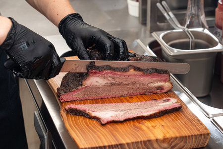 Cutting smoked brisket into slices in the kitchen