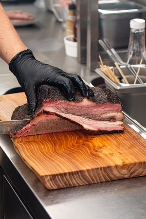 Cutting smoked brisket into slices in the kitchenの写真素材