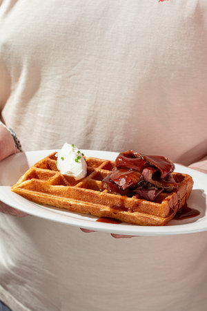 Man holding plate of waffle with brisketの写真素材