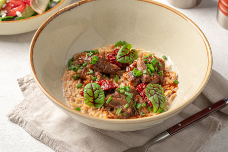 Portion of pasta orzo with meat and basilの写真素材