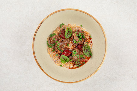 Portion of pasta orzo with meat and basilの写真素材