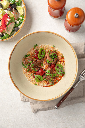Portion of pasta orzo with meat and basilの写真素材