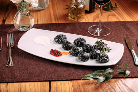 Gourmet black colored dumplings with sauceの写真素材