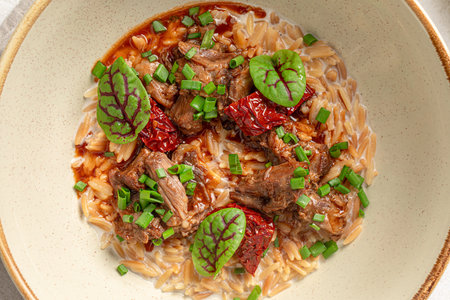 Portion of pasta orzo with meat and basilの写真素材