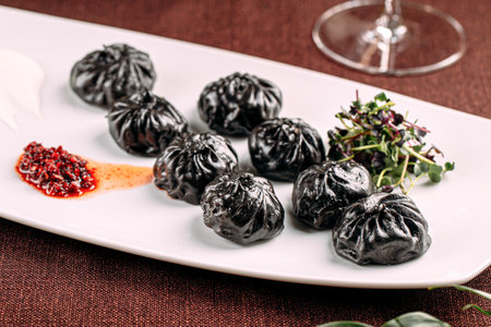 Gourmet black colored dumplings with sauceの写真素材
