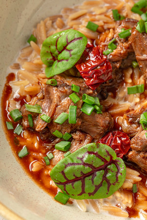 Portion of pasta orzo with meat and basilの写真素材