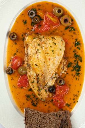 Portion of dorado fish with puttanesca sauceの写真素材
