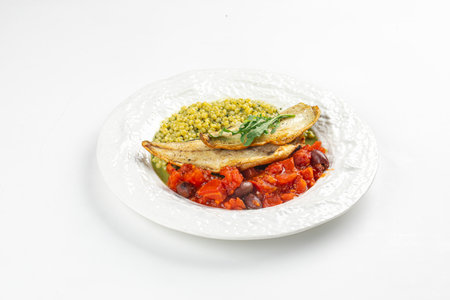 Portion of sea bass fillet with ptitim and tomatoの写真素材