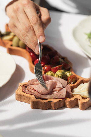 Eating meat delicacy with a fork from appetizer platter