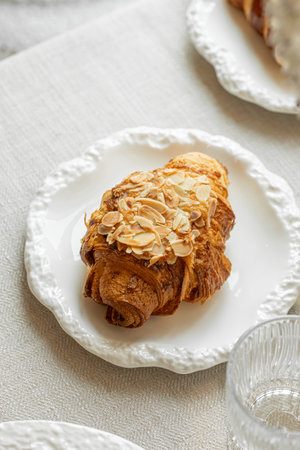 Almond croissant served with coffee on white plate