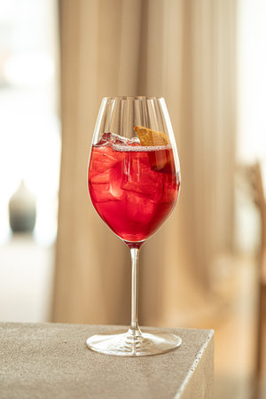 Red cocktail with orange and ice in wine glass