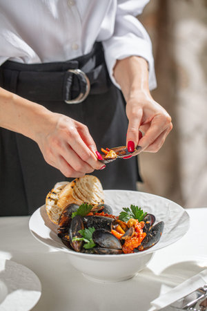 Woman opening mussel over seafood bowl