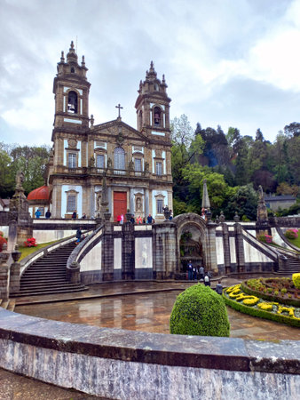 Braga Portugal March 29 2024 Baroque church of Bom Jesus do Monte with visitors climbing stairways and flower beds in foregroundの写真素材