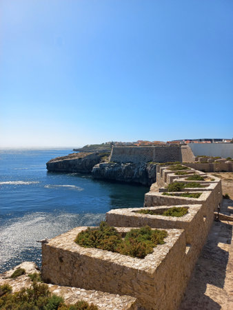 Peniche, Portugal. July 21 2024 Rugged limestone fortress walls overlooking the deep blue Atlantic Ocean in Peniche under bright midday sunの写真素材