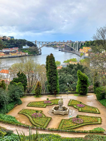 Porto, Portugal. March 30 2024 formal garden terrace with fountain in the foreground, overlooking the Douro River and the iconic Ponte da ArrÃ¡bida arch bridge under a moody sky.の写真素材