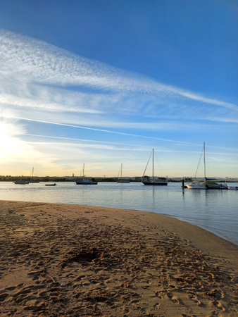 Bright sunny day in Seixal marina showcasing sailboats anchored in calm river clear blue sky vapor...