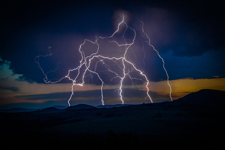 Multiple lightning strikes on distant mountainの写真素材