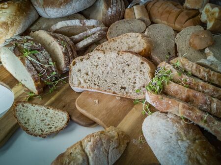 Selection of crusty sliced breads on wooden cutting boardの写真素材
