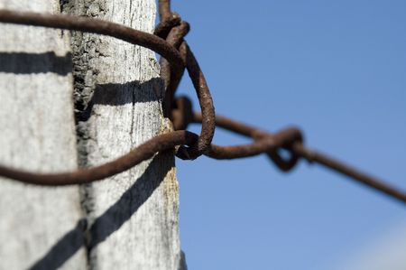 Rusty wire on post, blue skyの写真素材
