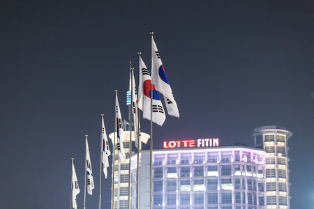 Dongdaemun, Seoul, South Korea- March 2019: Korea national flags shoot with Lotte Fitin as background.のeditorial素材