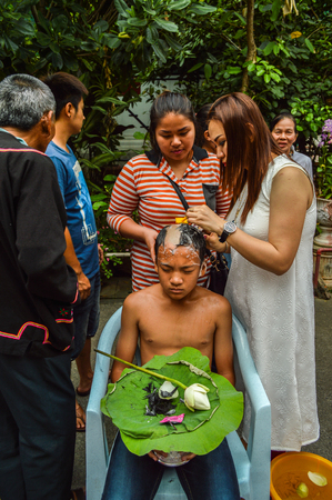 Chiang Rai, Thailand - April 1, 2017 : Ordination ceremony at Wat Phra Keaw. Young boy gets head shaving.のeditorial素材