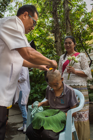 Chiang Rai, Thailand - April 1, 2018 : The Ordination Ceremony of the 2018 Ordination Program at Wat Phra Kaew Chiang Rai, hair shaving before ordination. Father shaving the head of a boy to prepare him for novice.のeditorial素材