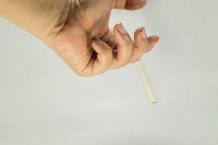 Hand holding a cigarette. Unlighted cigarette holden between two fingers.の写真素材