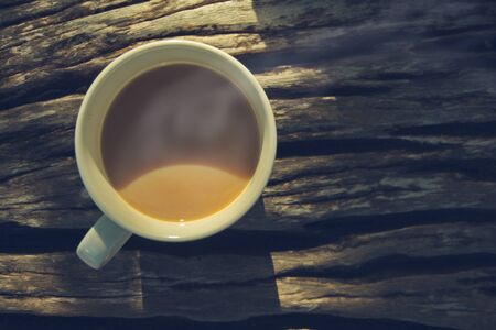 In the morning, top view of a coffee cup placed on an old wooden bench.の写真素材