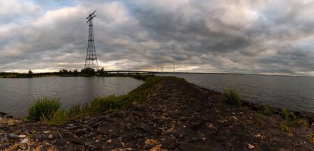 Electric tower near river and bridge in the Netherlandsの写真素材