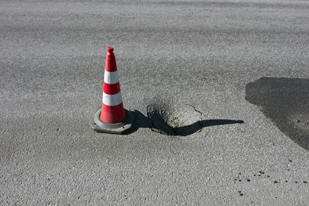 Pothole damage with traffic cone on road