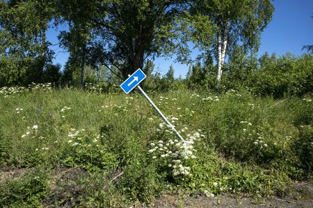 tilted traffic signpost with arrow pointing upper rightの写真素材