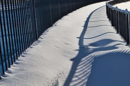 Shadows from the hand-rail on the snow on a sunny dayの写真素材