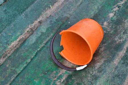old orange plastic bucket in a weathered green fibreglass boatの写真素材