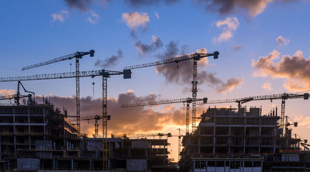 Industrial construction cranes and building silhouettesの写真素材