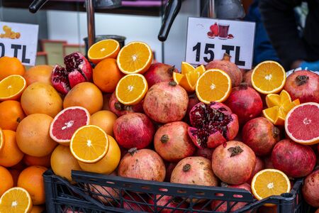 Lots of orange and pomegranate fruits in plastic black crates. Photographed in front of the...