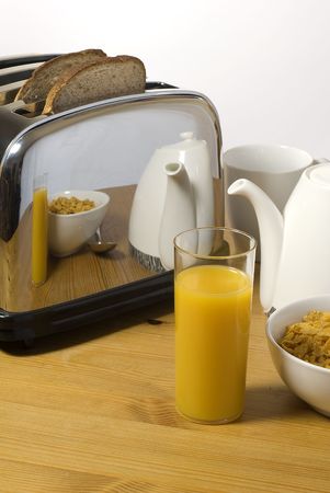 Breakfast orange juice and cereal with reflection in toaster
