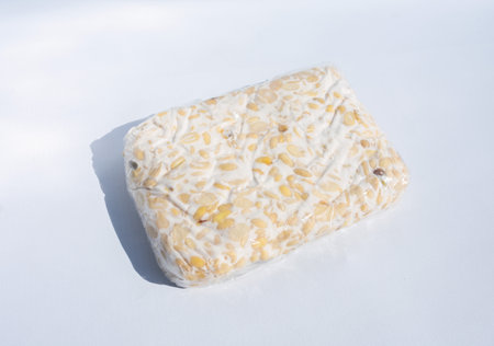 Raw tempeh or tempeh, wrapped in transparent plastic. Tempe is a traditional Indonesian food made from fermented soybeans. isolated in white background.の写真素材