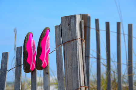 Swim shoes on wooden fence at beach sand dunesの写真素材